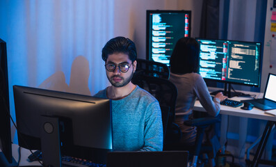 Wall Mural - asian and indian developer devops team working about coding promgram with software computer at night