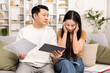 © puhhha - Stressed couple managing finances with tablet and papers, experiencing financial worry in a modern living room.