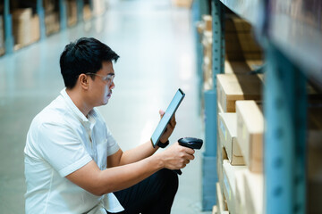 A man is looking at a tablet while holding a barcode scanner. He is in a warehouse and he is focused on his task