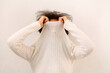 © Dasha Petrenko - Curly african woman covering face with sweater collar, female taking off polo neck jumper