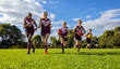 © Austockphoto - schoolchildren running towards camera in football uniforms on green grass