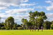 © Austockphoto - several kids in footy uniforms running towards goalposts on football field