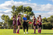 © Austockphoto - smiling female coach holding clipboard addressing schoolchildren in sports uniforms