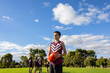 © Austockphoto - 12 year old boy on football field with teammates in background with blue sky and clouds