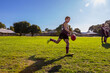 © Austockphoto - schoolboy backlit kicking football with teammates watching on in background