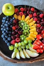 A Black Plate With The Colors Of The Rainbow In It, With Fruit On Top Cherries, Blueberries, Grapes, Strawberries, Kiwis, Raspberries, And A Yellow Apple The Piece Is In The Style Of An Abstract Artis