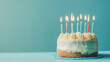 © Erwin - Classic vanilla birthday cake with blue lit candles and delicious vanilla frosting on soft blue