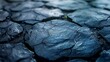   A tight shot of a blue-hued rock surface, adorned with water droplets, boasts intricate cracks