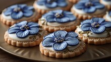   A Tight Shot Of A Plate Filled With Cookies, Each Topped With Frosting And Blue Blooms