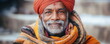 Smiling old Indian man in traditional clothes on blurry city background. Elderly immigrant with grey beard and turban portrait. Social support.