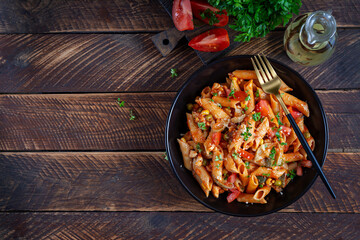 Canvas Print - Classic italian pasta penne arrabbiata with vegetables on wooden table. Penne pasta with sauce arrabbiata. Top view, overhead