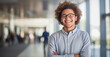 © Darya - A cheerful young man with curly hair and glasses standing confidently in a bright office hallway, arms crossed, exuding a welcoming, professional vibe.