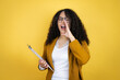 African american business woman with paperwork in hands over yellow background shouting and screaming loud to side with hand on mouth