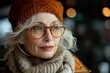 A retired, charming senior lady in a knitted hat and glasses exudes positive energy outdoors.