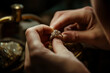 A person is holding a gold ring and polishing it. The ring is on a table and there is a bottle nearby