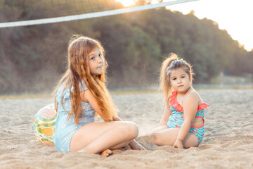 Wall Mural - Two little brunette and ginger sisters playing on the beach