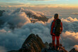 A person is standing on a mountain top, looking out over the clouds