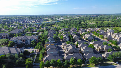 Two story single family houses near new development apartment complex surrounding by lush green trees along Brushy Creek Road with E Whitestone Blvd background Cedar Park, Austin, Texas, aerial