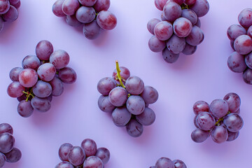 Wall Mural - Fresh organic grapes on a vibrant purple background, flat lay composition with top view