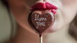 Closeup of woman holding chocolate heart shaped lollipop with text love you