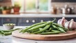 A selection of fresh vegetable: green beans, sitting on a chopping board against blurred kitchen background; copy space
