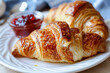 Two croissants on a white plate with a jelly spread