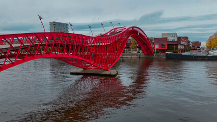 Wall Mural - Aerial drone view of modern footbridge Python Bridge at Eastern Docklands neighborhood of Amsterdam Netherlands