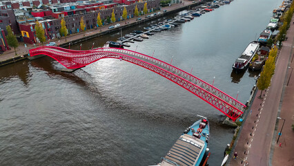 Wall Mural - Aerial drone view of modern footbridge Python Bridge at Eastern Docklands neighborhood of Amsterdam Netherlands