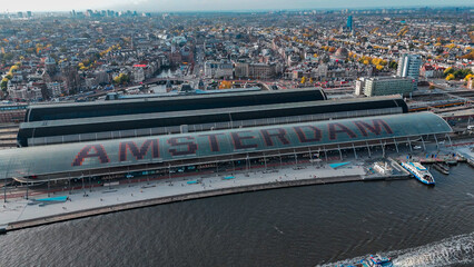 Wall Mural - Aerial drone view Amsterdam Central Train Station with Amsterdam sign on roof. Bird's eye view autumn cityscape