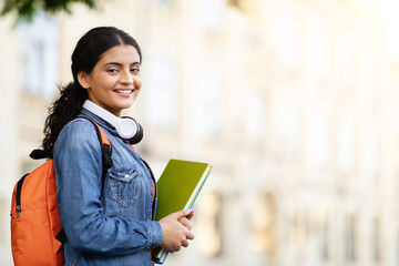 Happy Indian student with working books outside