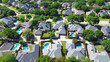 Shingle roofing of large two story suburban upscale houses lush greenery tree, swimming pool, large fenced backyard, well maintained HOA landscape in subdivision suburb Dallas, Texas, aerial view