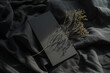 mock-up with black business card laying in black cloth with a small natural branch on top of it