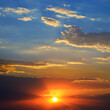 Dramatic sunset background with bright sun, blue sky and clouds.