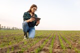 Fototapeta Kuchnia - Woman Farmer on a green wheat field with a tablet in his hands. Organic green wheat in the field. Smart farm. Agro business. Harvesting.
