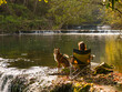 Woman enjoys a moment of tranquillity by the river with an attentive dog by side