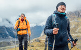 Fototapeta  - Caucasian and Sherpa men backpackers with trekking poles together hiking and enjoying Mera peak climbing acclimatization walk Makalu Barun Park route. Men enjoying Togetherness and beautiful valley.