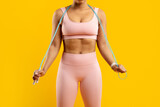 Fototapeta Tulipany - Fit lady with jump rope on yellow background