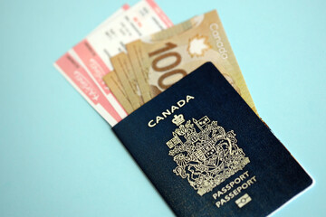 Wall Mural - Canadian passport with money and airline tickets on blue background close up. Tourism and travel concept