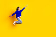 Full length photo of pretty teen girl jumping running fast superhero wear trendy knitwear blue outfit isolated on yellow color background
