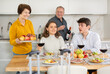 © JackF - Friendly young girl and guy enjoying festive family dinner, spending time with elderly parents over wine and light snacks in cozy kitchen..
