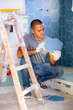Man working in bathroom in apartment, setting tile, doing renovation works.