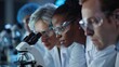 A group of scientists huddled together in a laboratory their eyes focused on a microscope as they yze and discuss the results of their research their white coats and safety goggles .