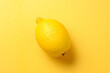 A vibrant, freshly picked lemon rests enticingly atop a cheerful yellow backdrop, radiating zestful energy and promising a burst of citrusy delight with every slice