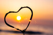 Heart-shaped sparkler burning against background of sea and rising sun at dawn. Bengal fire in shape of heart sparkling at sunrise dawn and sunset on sea. Love infatuation Valentine's Day