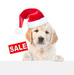 Funny Golden retriever puppy wearing santa hat shows signboard with labeled 