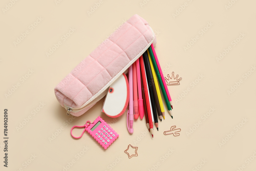 Pink pencil case with different school stationery on beige background