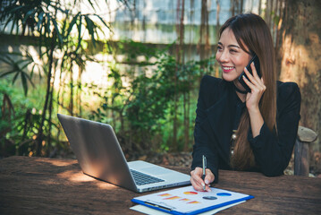 Poster - Asian Female freelance using laptop at home office desk. Woman reading financial graph chart Planning analyzing marketing data. Asian female people working office firm with business stuff, coffee cup