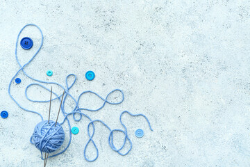 Sticker - Yarn ball with knitting needles and buttons on blue grunge background