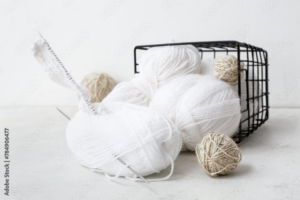Basket with yarn balls and knitting needles on white background