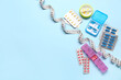 Containers, blister packs with weight loss pills and measuring tape on blue background